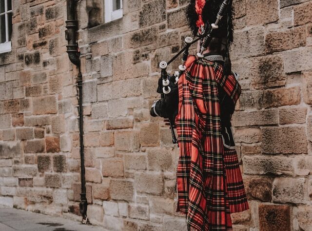 the back of a man playing the bagpipes